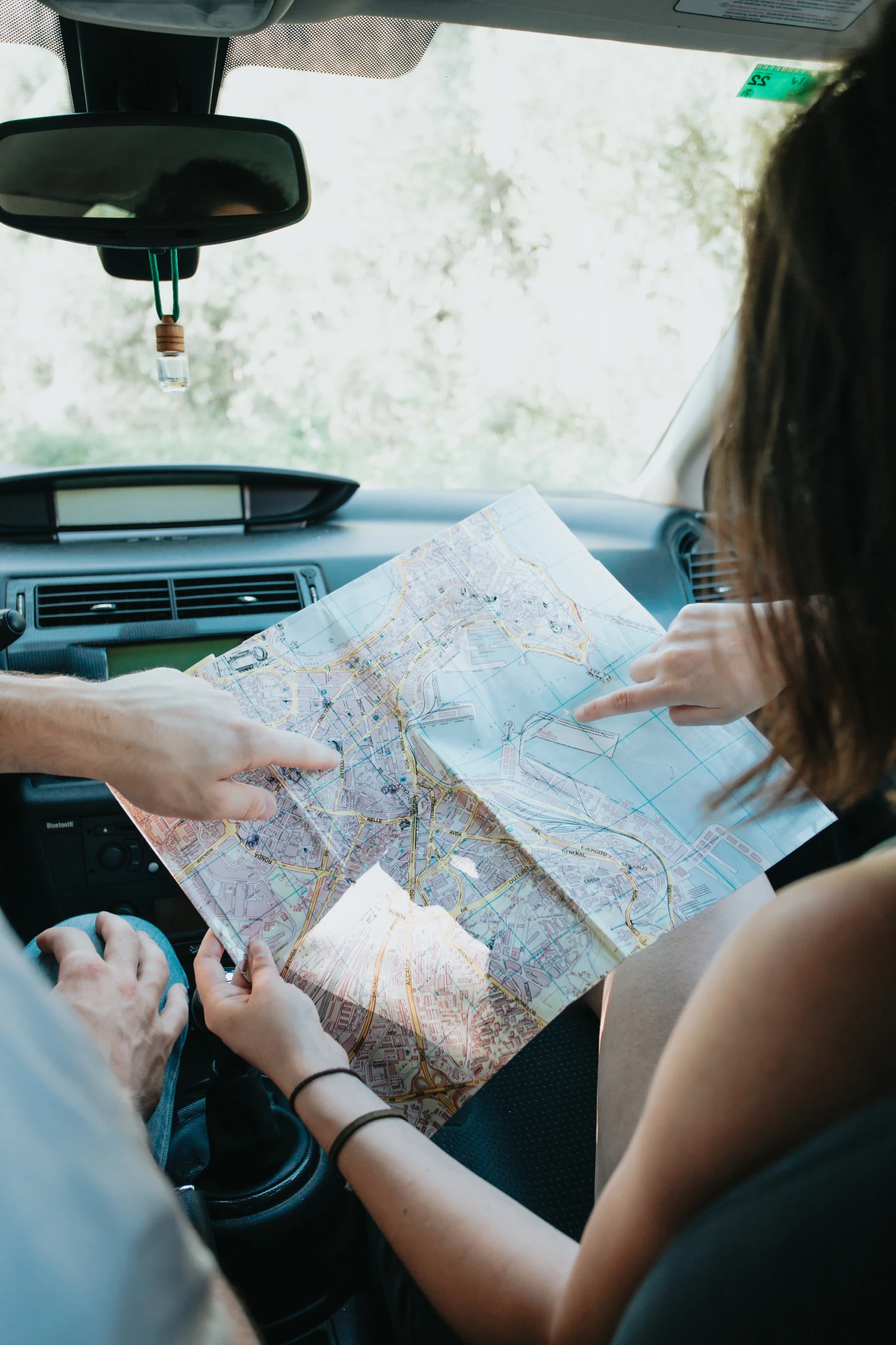 two people in a vehicle hold up a map