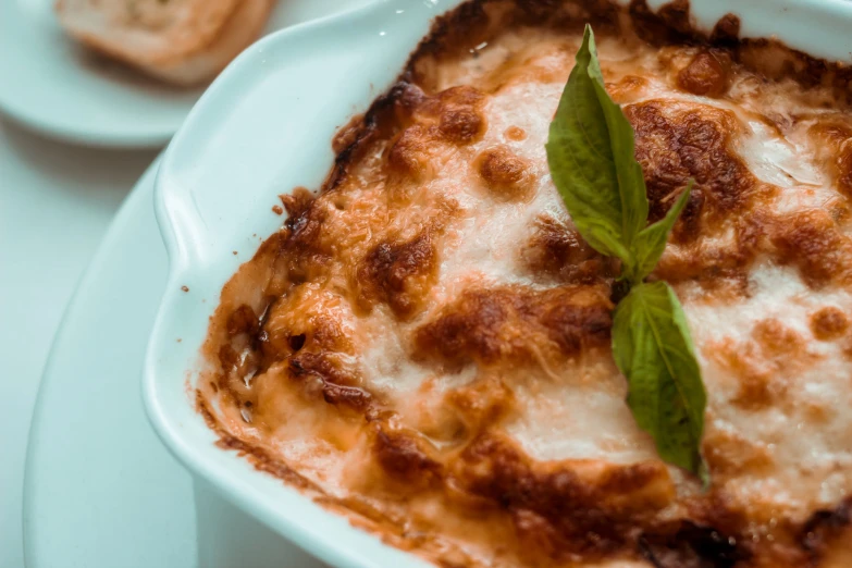 lasagna with cheese and sauce on plate with serving utensils