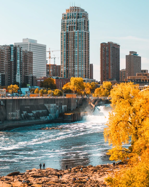 people are standing at a river in a city with tall buildings