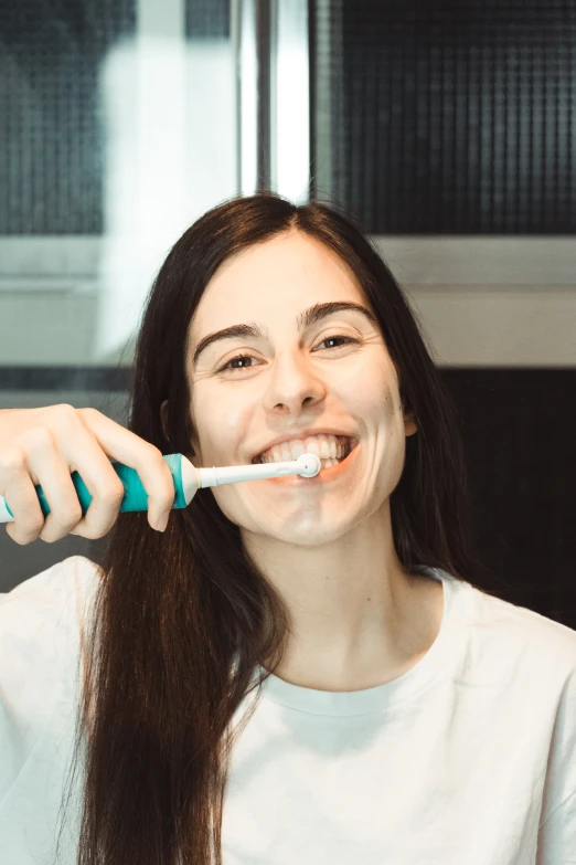 a woman brushing her teeth using a tooth brush