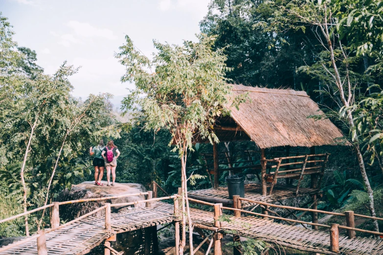 two people standing outside of a wooden hut on a deck