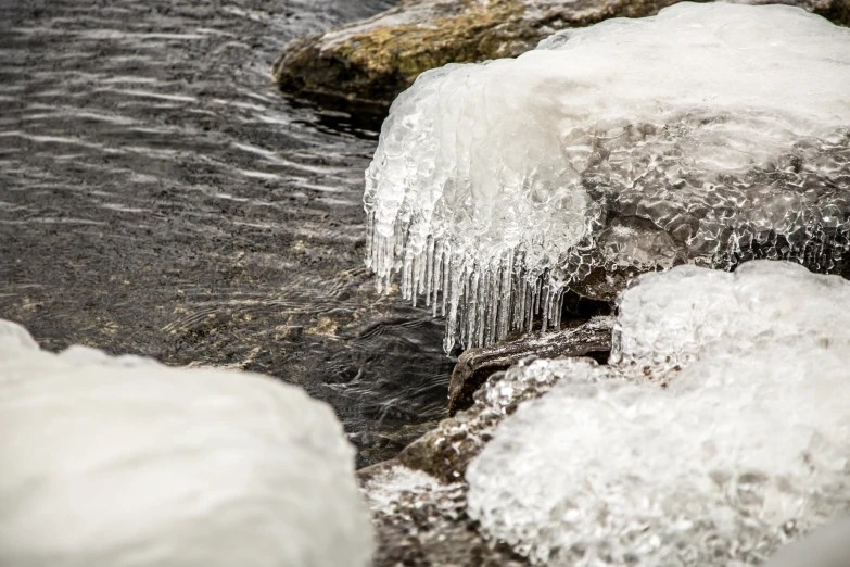 a close up view of ice and water near some rocks