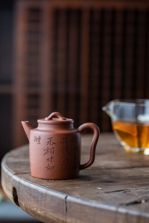 a tea pot sitting next to a glass cup