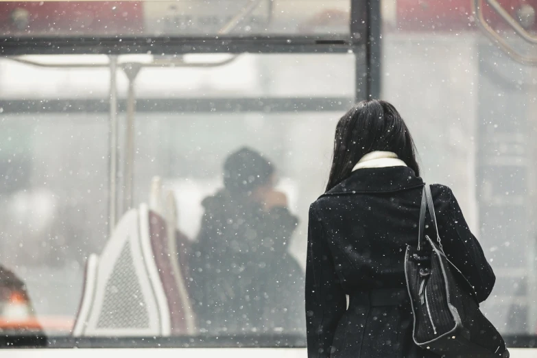 a woman walking away from her bus stop during the rain