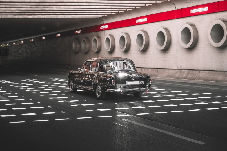 an old classic car driving along the underground road