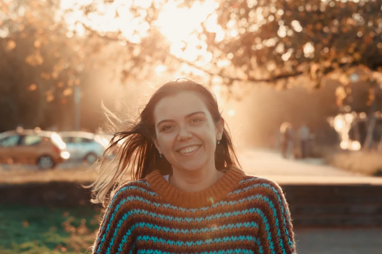 a woman smiles as she stands on the sidewalk