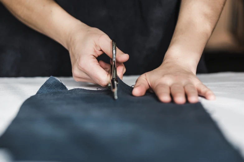 someone using scissors to cut fabric on a bed