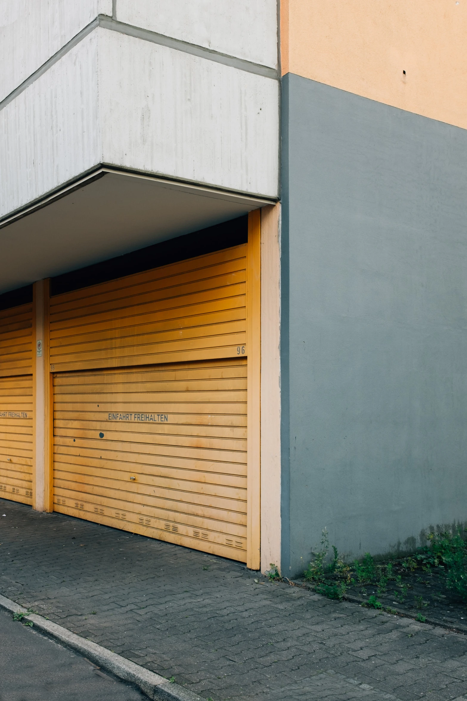 an empty garage with two doors on a sidewalk