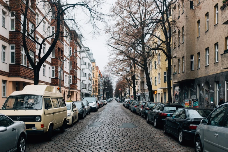 the street is lined with parked cars, and there are trees on either side