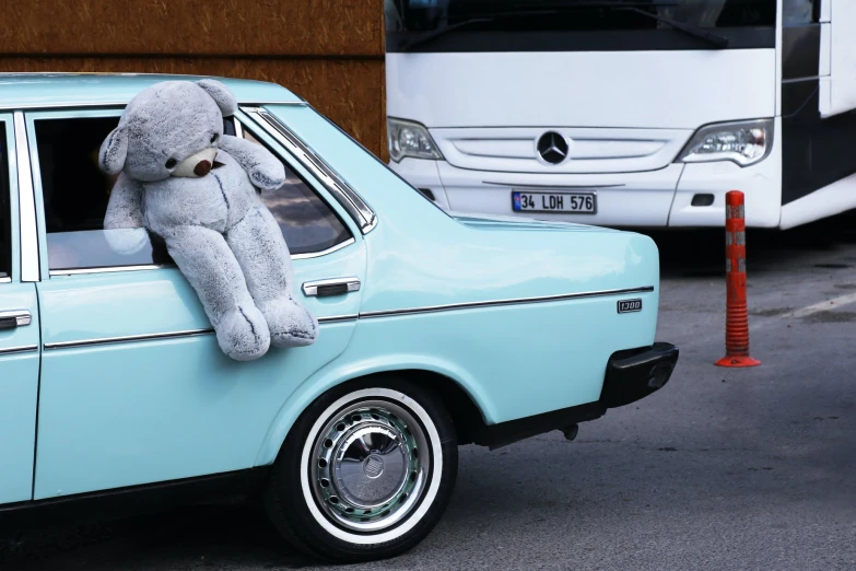 a blue car with a stuffed bear sticking its head out