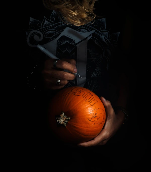 a person holding an orange on a black background