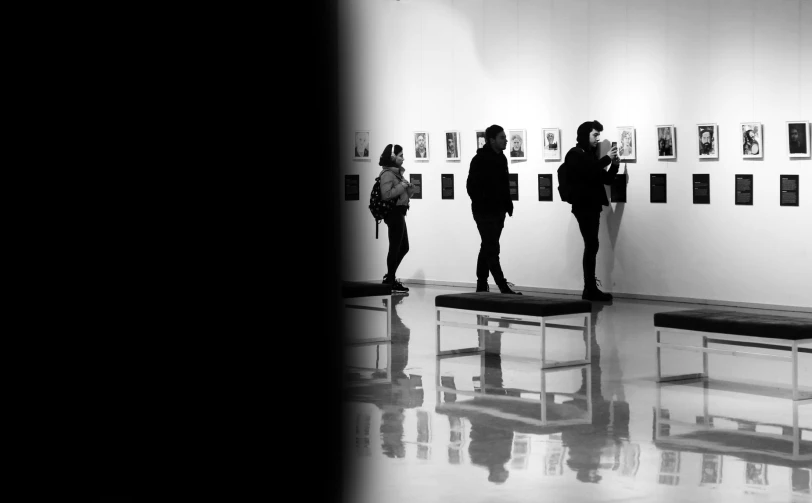 three people standing in front of a wall with pictures on it