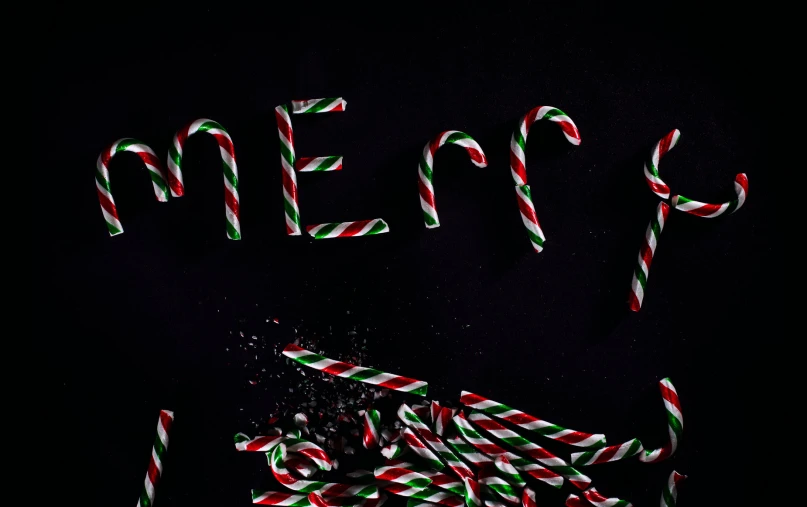 some candy canes and some letters that are on a black surface