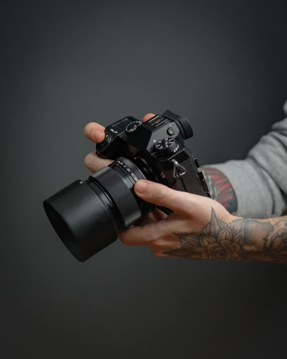 a person with a tattoo holding onto two cameras