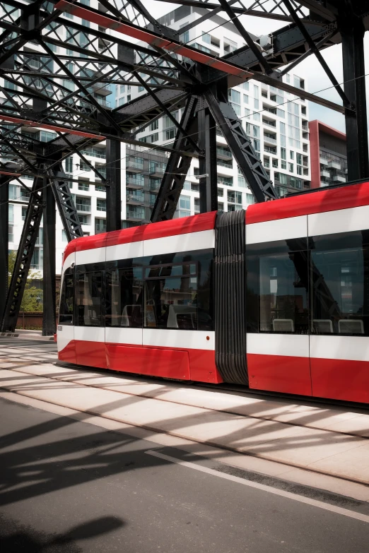 a long passenger train sitting under some tall buildings