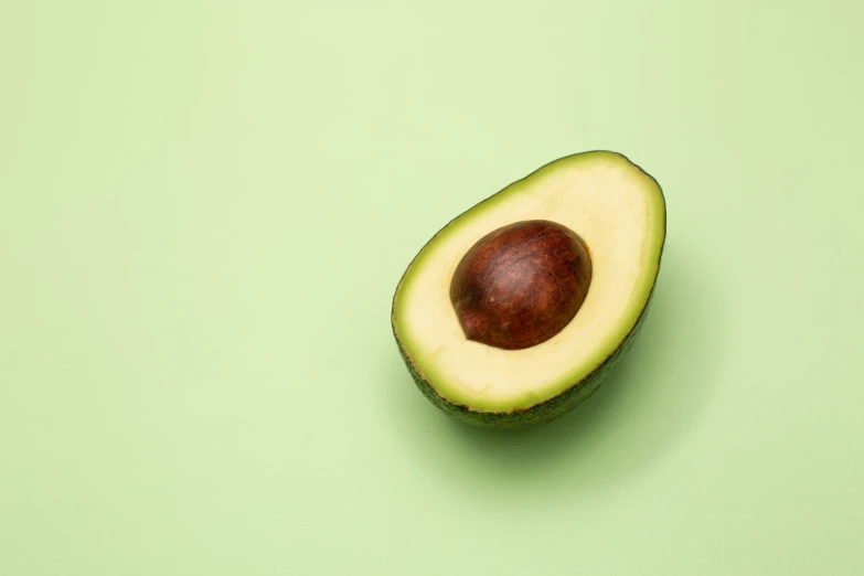 avocado cut in half and on green background