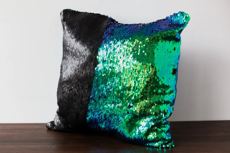 a square pillow covered in green and black sequins