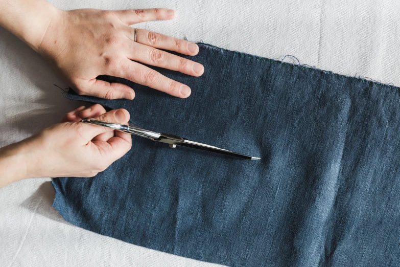 a pair of hands crissing fabric with scissors