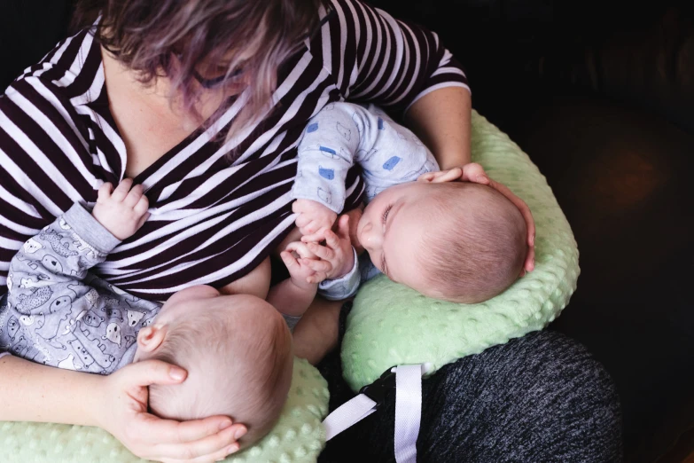 a woman in a black striped top holds a sleeping baby