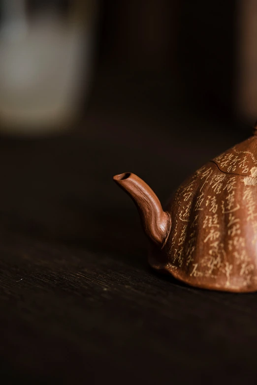 the miniature brown teapot is laying down on a table