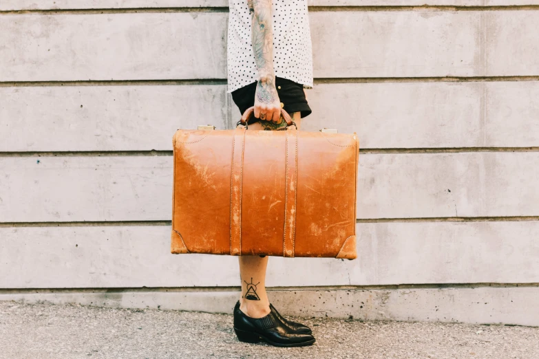 a woman in black shoes holding a brown suitcase