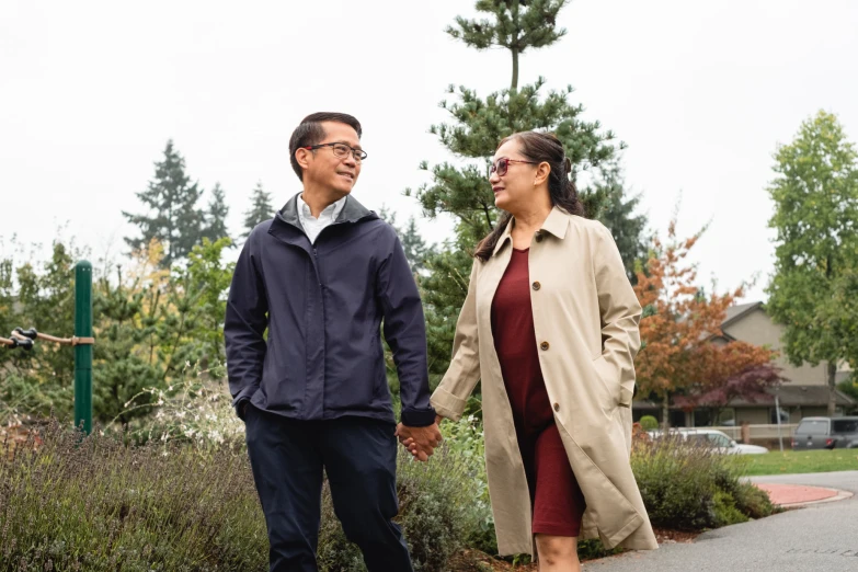 an older man and woman holding hands in front of some bushes