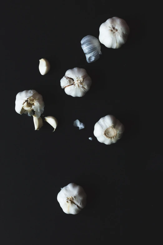 peeled garlic and heads on a black background