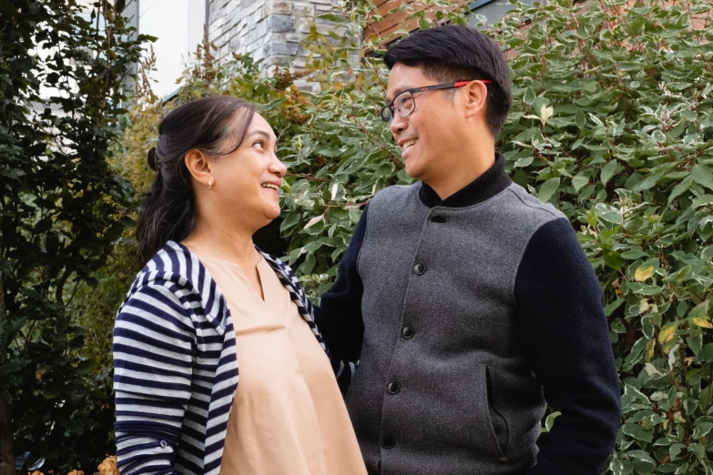 a man and woman standing in front of a fence