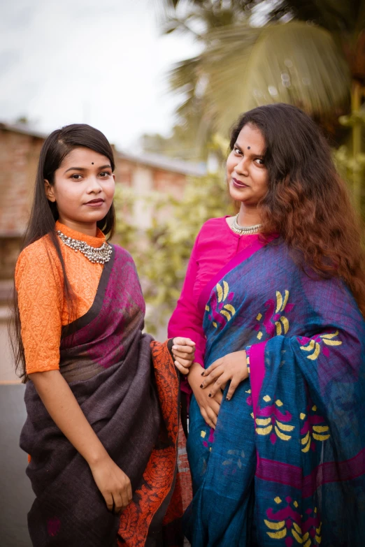 two young women wearing colorful dresses pose for a picture