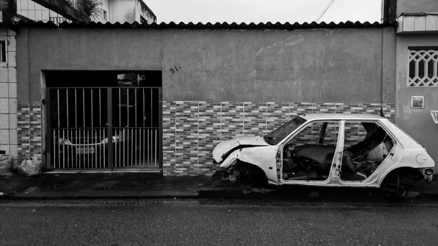 a broken down white car parked outside of a building