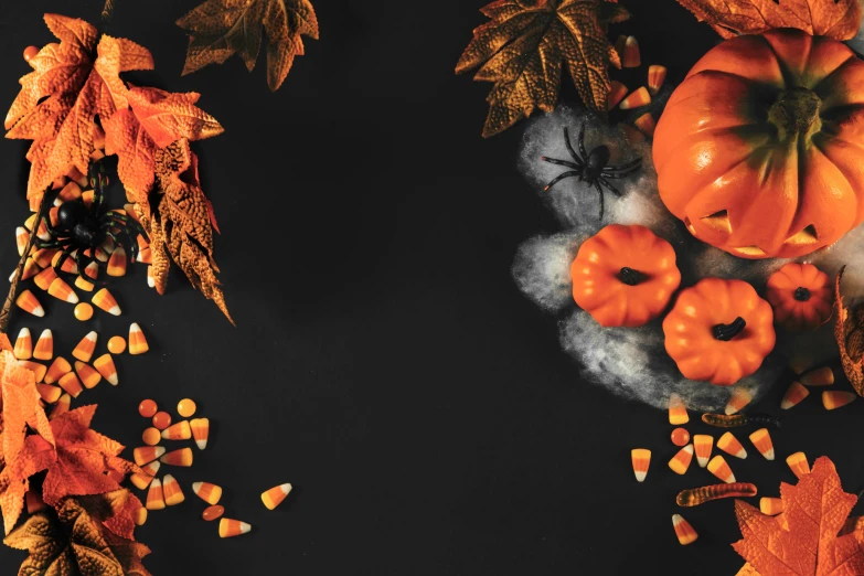 candy corn and candy decorations are arranged around pumpkins