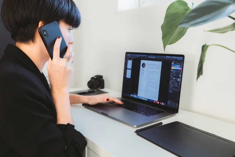 a woman is using a laptop with a phone