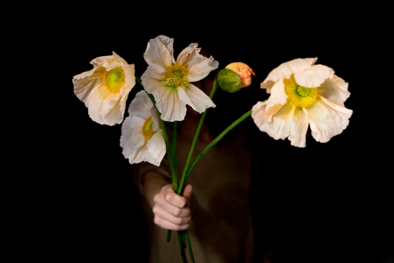 the woman is holding five white and yellow flowers