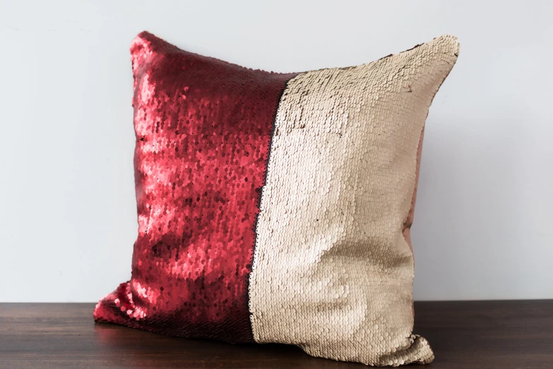 the red and beige throw pillow is on the wooden table