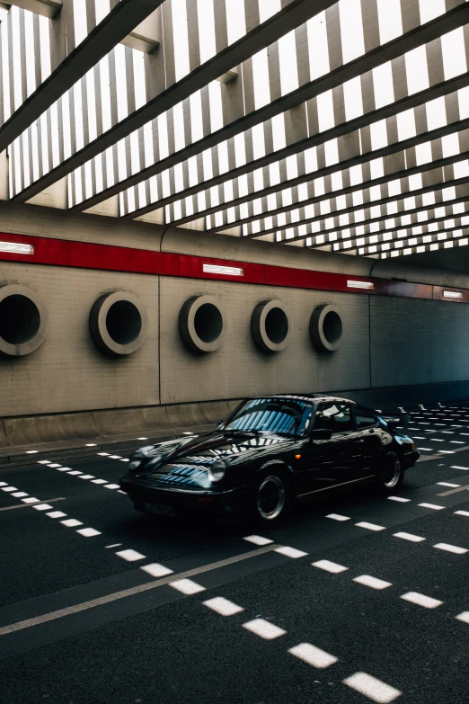 a black car on the side of a street next to a wall