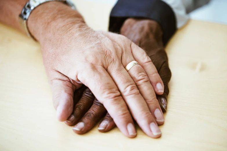 two hands holding each other on the edge of a table