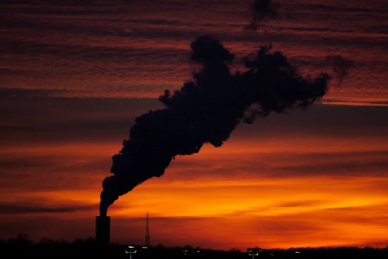 smoke from pipe blowing in front of cloudy sky