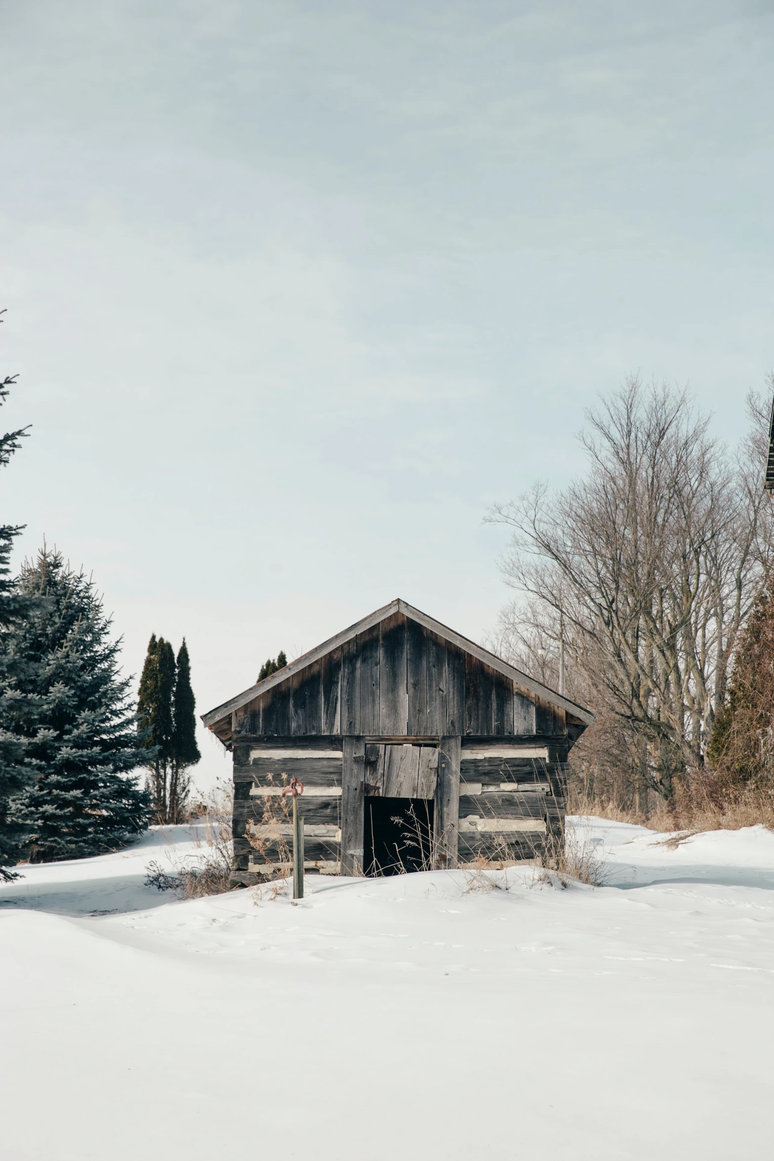 a rustic log cabin sits in a snow covered field