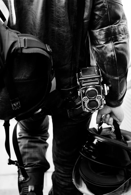 man carrying a camera while standing on a sidewalk