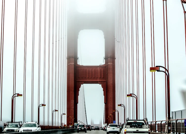 cars passing through a foggy, tall bridge