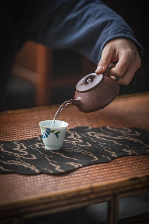 someone pouring tea into a cup from the top