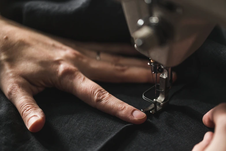 person sewing and wearing a black cloth