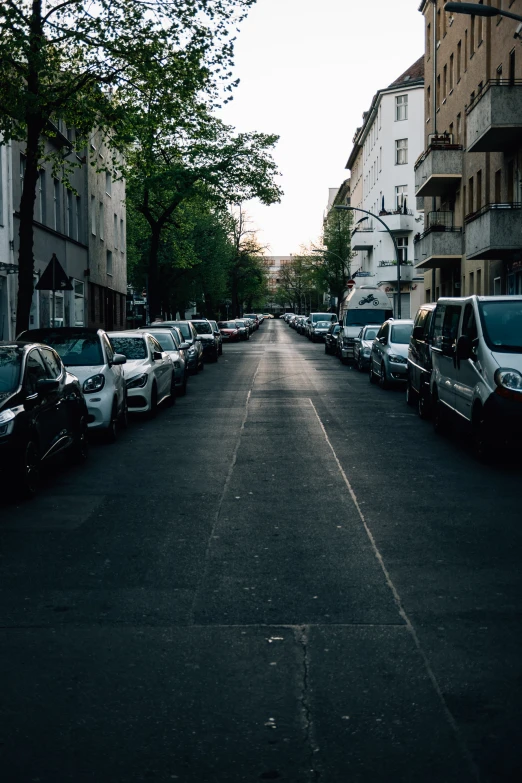 a wide street is lined with parked cars