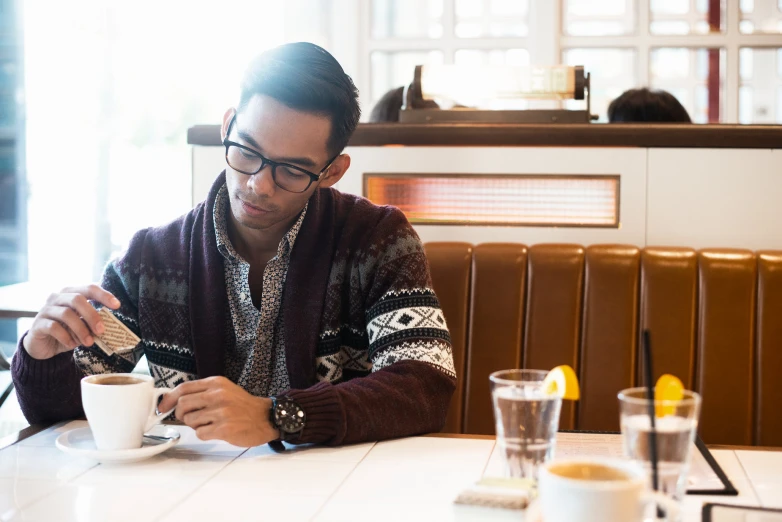 man sitting at table with a cup and paper in front of him