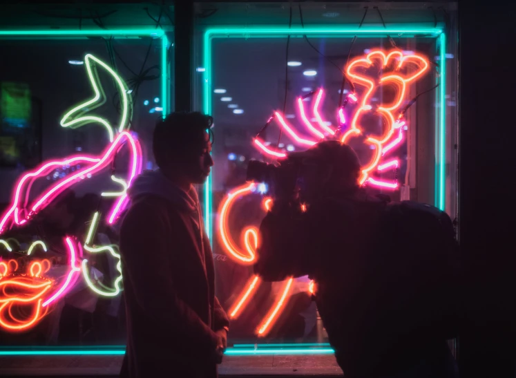 two people standing in front of colorful neon signs