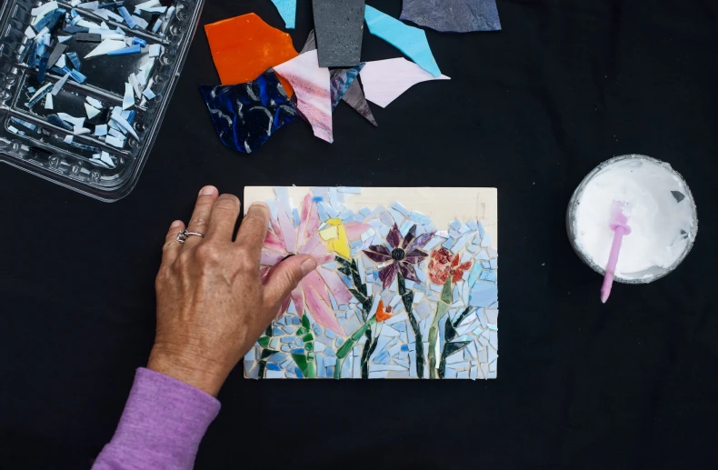 a person's hand near an art project on a table