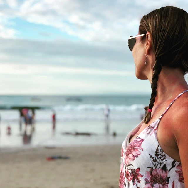 a woman with sunglasses looking at people playing in the water