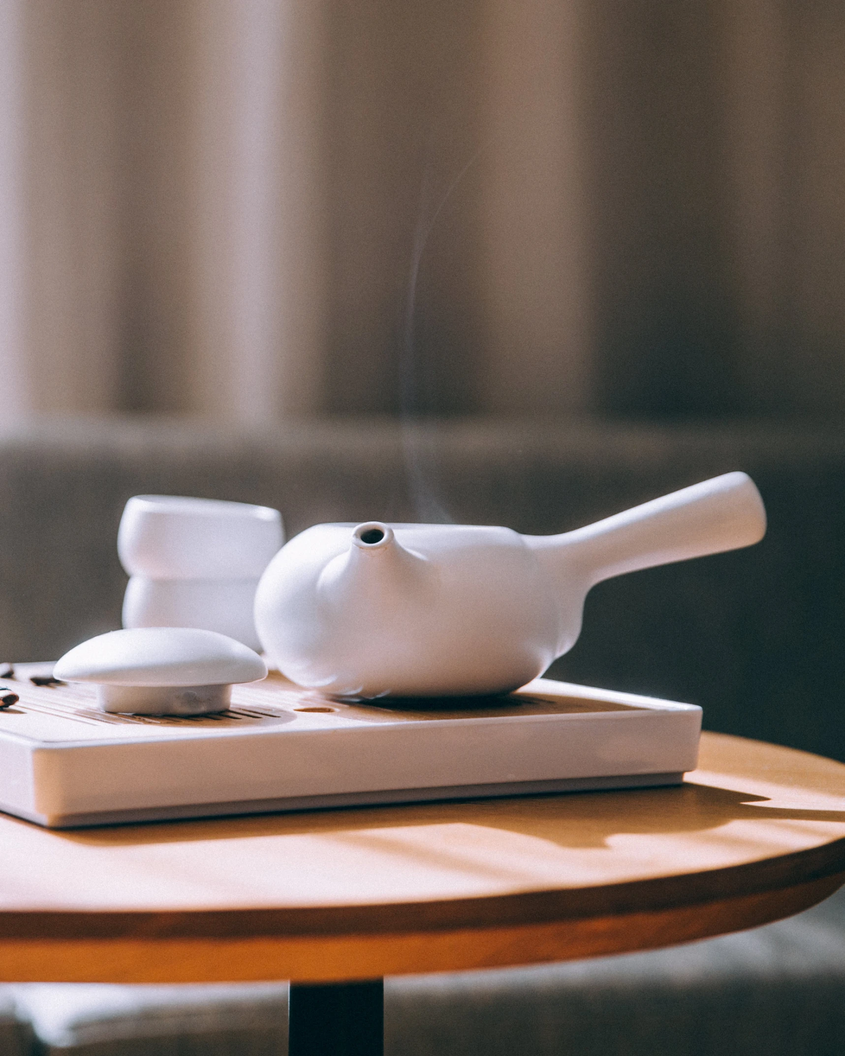 a wooden table with a white vase and remote controls on it