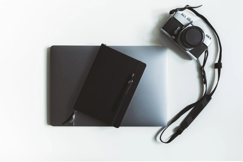 a laptop and a pen with an external external camera are on a white surface