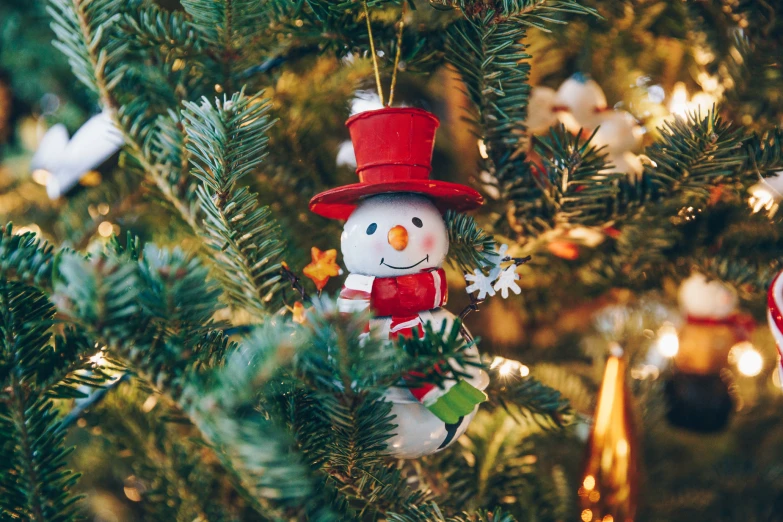 snowman ornament with red hat and snowflake on tree